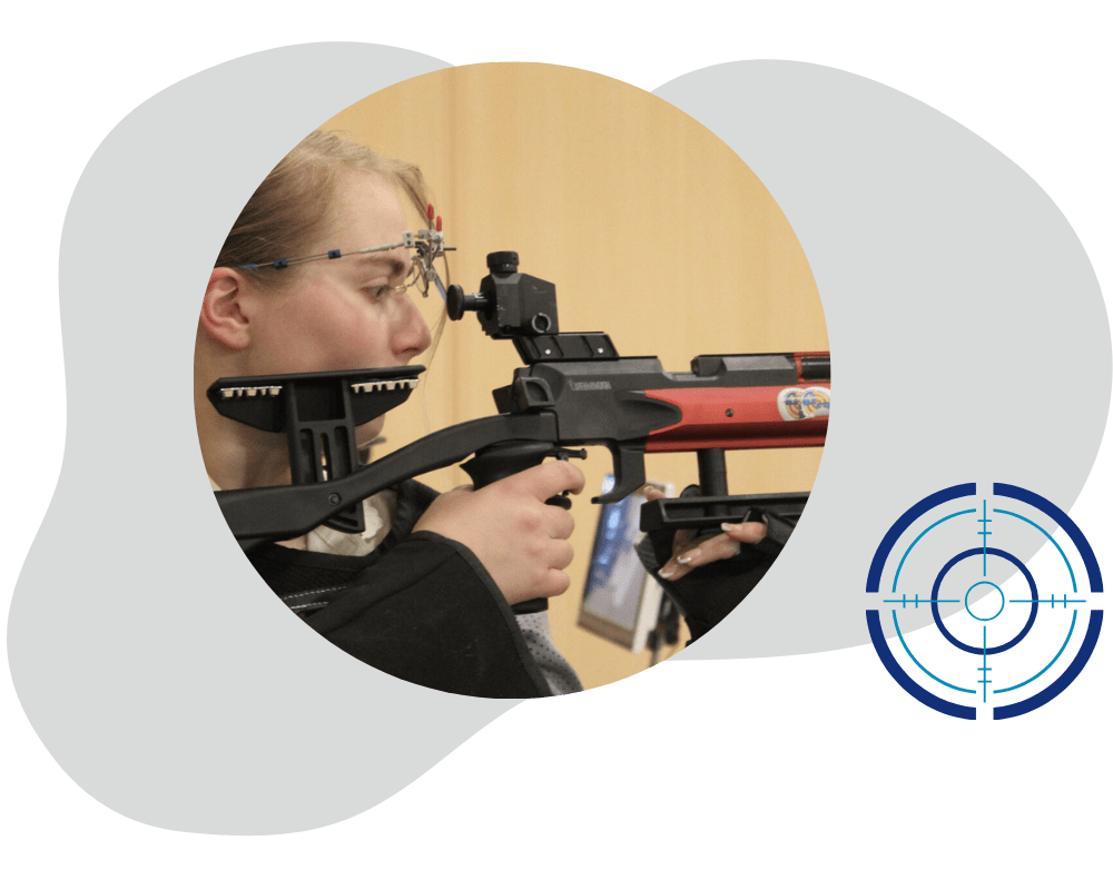 Design ohne Titel(39) Frau zielt mit einem modernen Luftgewehr auf eine Schießscheibe in einer Schießhalle. Im Vordergrund ist ein stilisiertes Fadenkreuz-Logo zu sehen.